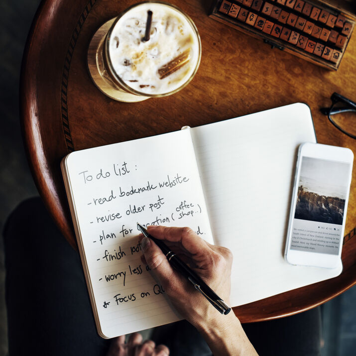 A person writing in a journal in the morning with soft sunlight, representing simple morning journaling prompts for focus, gratitude, and daily planning.